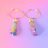 a pair of gold hoop earrings with a pink background